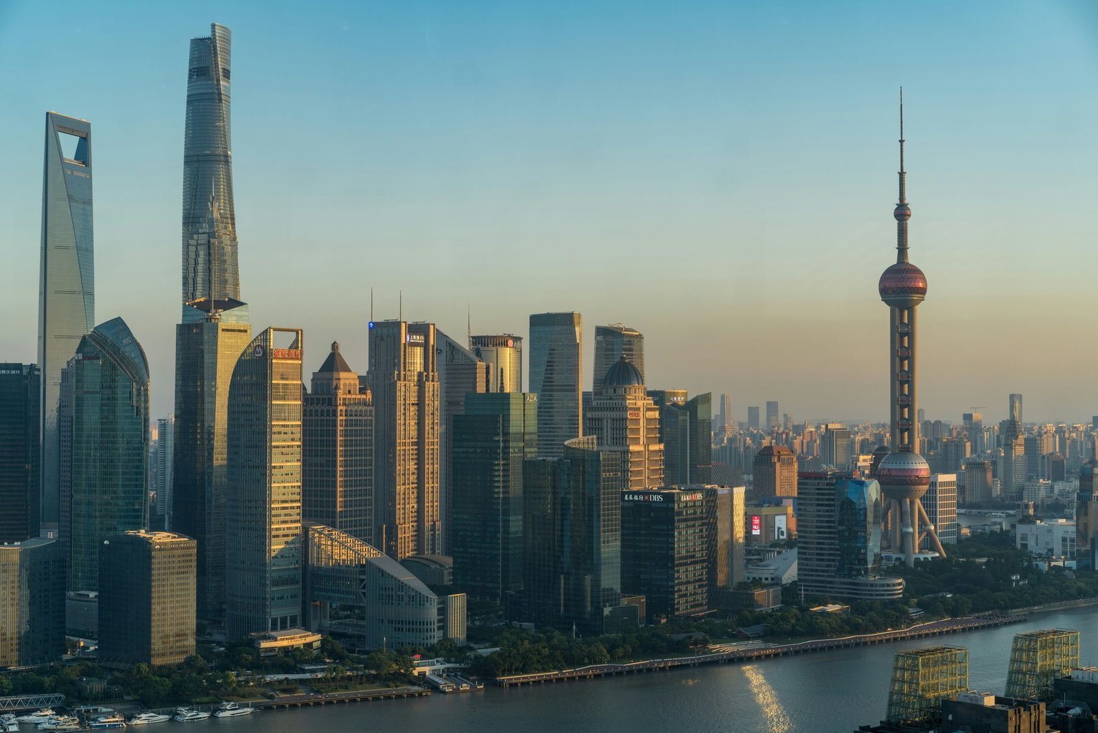 Skyscrapers and a tower with spheres catch warm light above a river