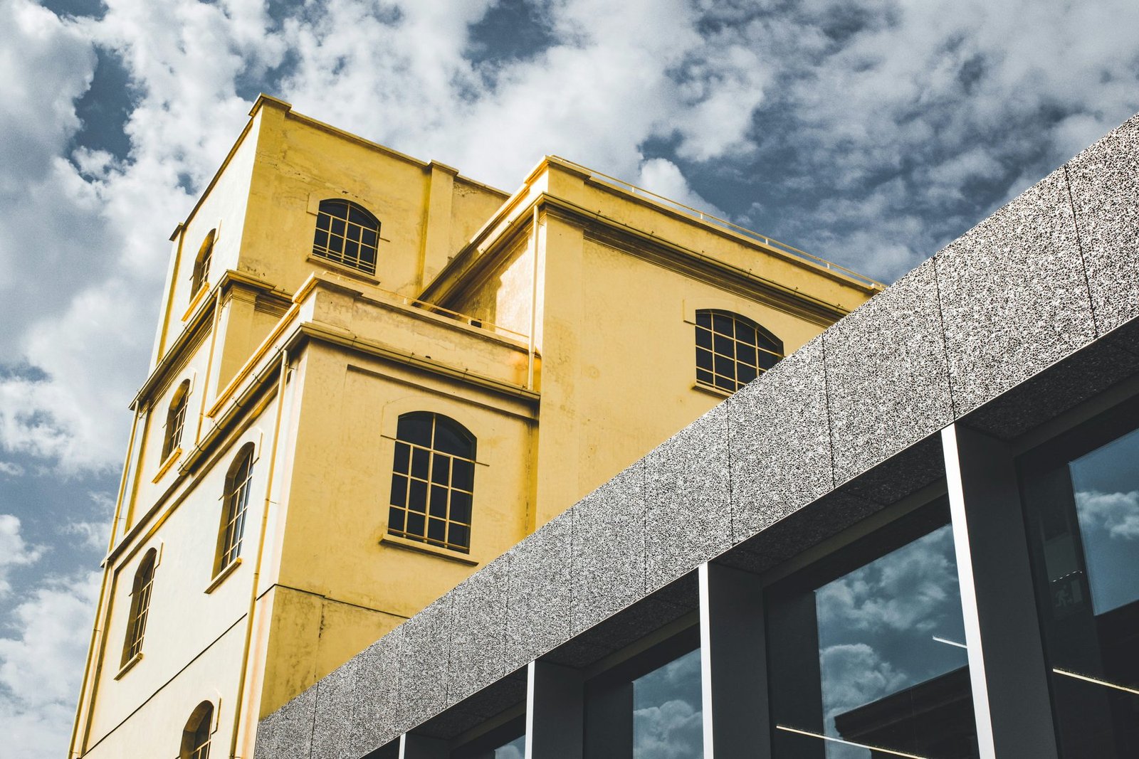 A building covered in gold leaf rises behind a gray textured wall under a cloudy sky