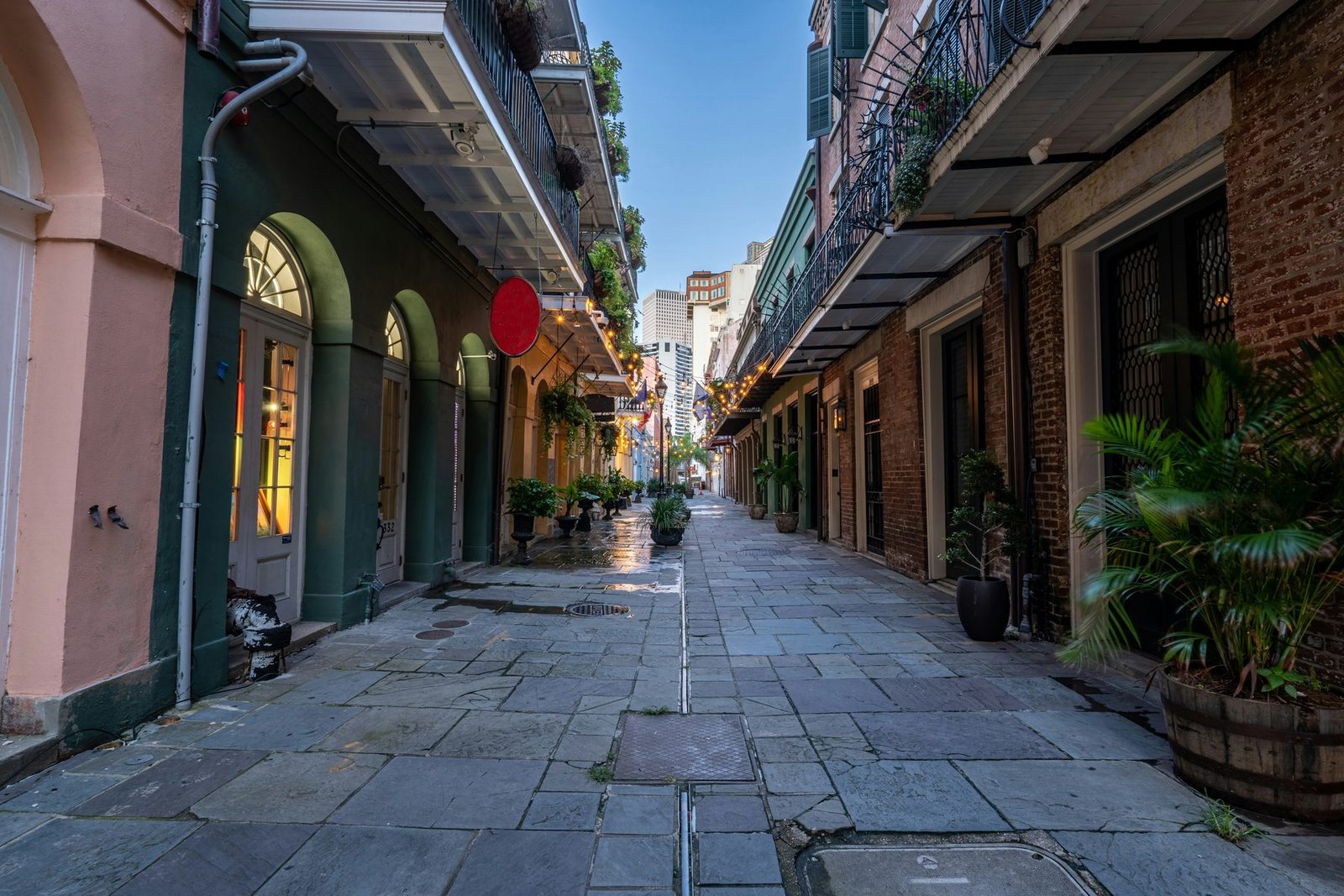 A narrow flagstone lane between old buildings with arched doorways and iron balconies, a red balloon hanging on one side